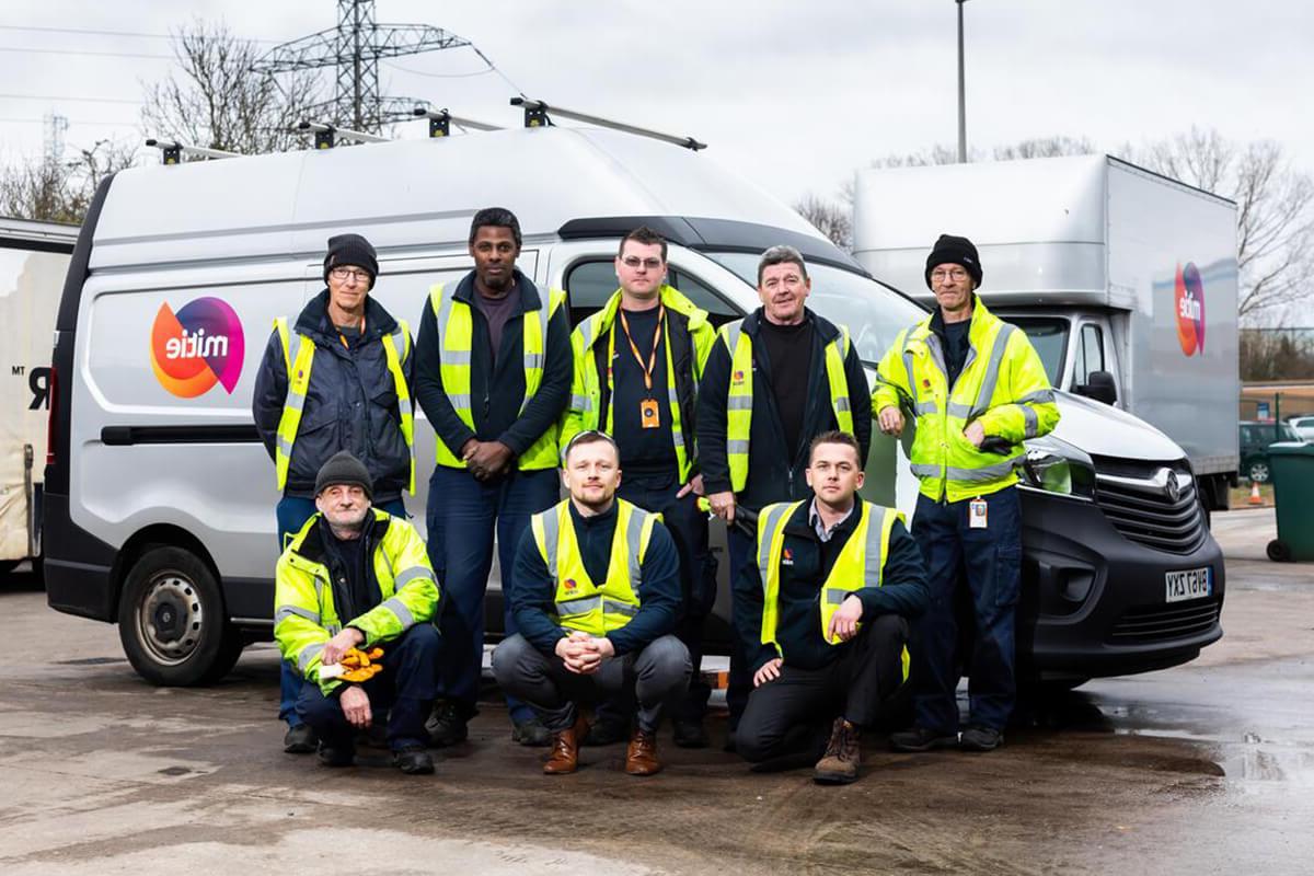 Team of Mitie workers in high-vis standing in front of a company van