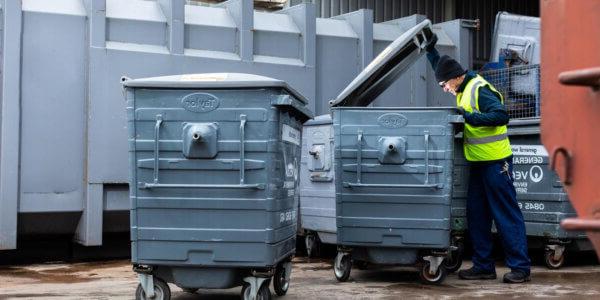 Mitie waste employee wearing high vis looking in a commercial waste bin